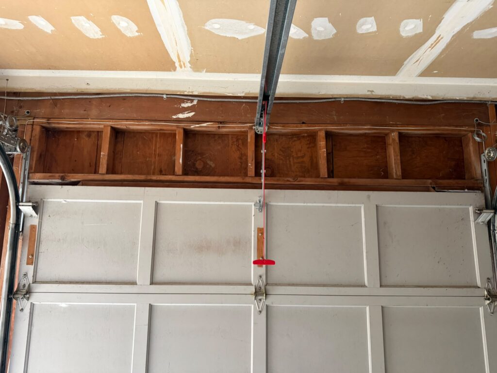 Garage door opener rail and red manual release cord seen from inside a garage